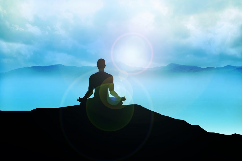Silhouette of a man figure meditating on the mountain